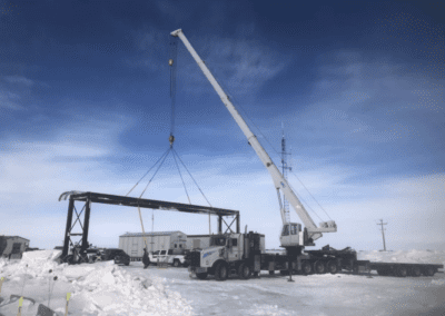 A crane is hoisting a substantial piece of equipment, demonstrating its capability in heavy lifting operations on a construction site.